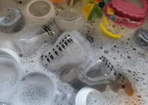 Sink full of baby bottles and various baby toys