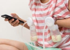 Mom pumping milk and playing on smartphone