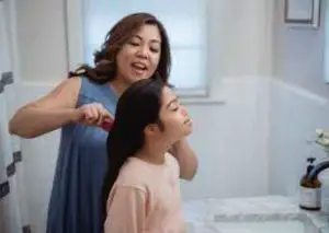 Mother combing her daughter hair